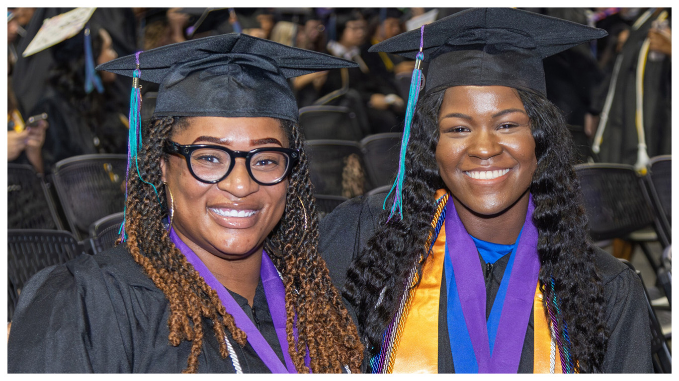 FSW students smiling and posing for a photo at commencement ceremony.